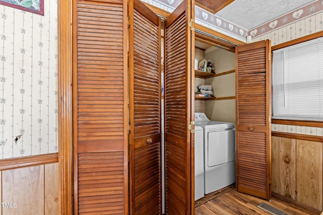 laundry room featuring washer and dryer, a textured ceiling, and light hardwood / wood-style floors