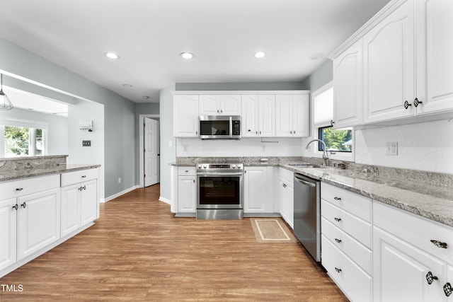 kitchen with white cabinets, stainless steel appliances, light wood-type flooring, and plenty of natural light