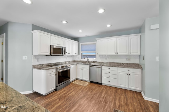 kitchen featuring backsplash, dark hardwood / wood-style flooring, white cabinetry, sink, and stainless steel appliances