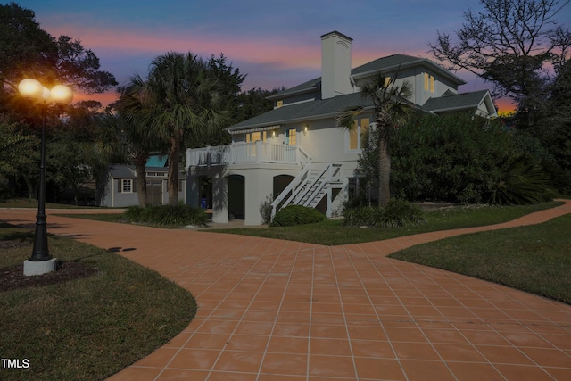 back house at dusk with a patio area and a yard