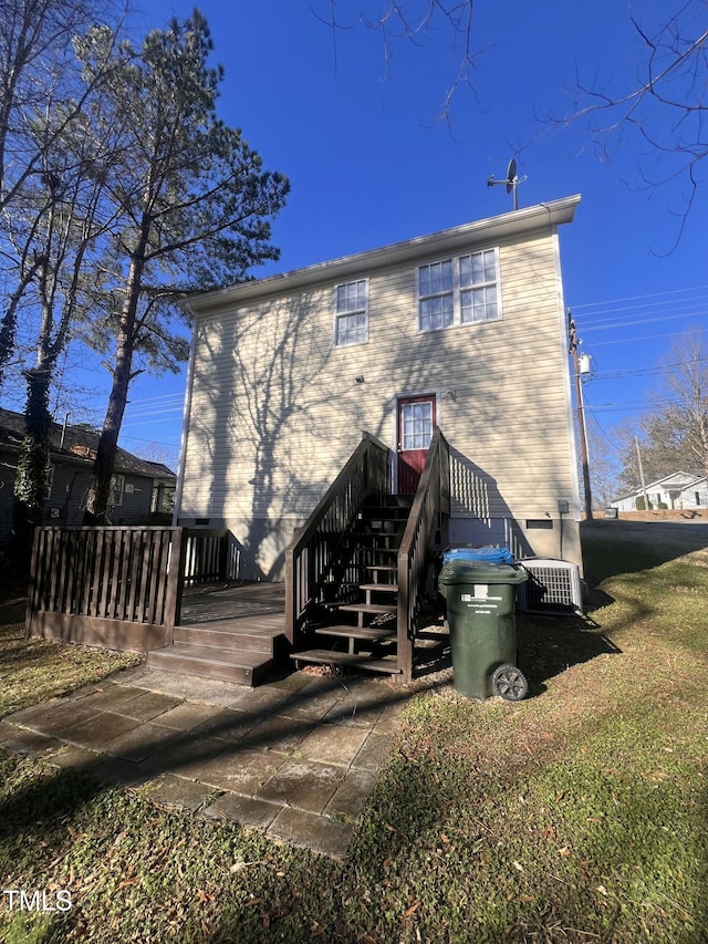 rear view of house featuring central AC unit and a lawn