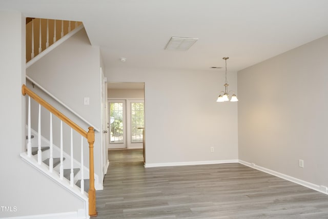 empty room with hardwood / wood-style floors and an inviting chandelier