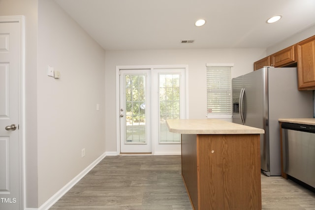 kitchen featuring stainless steel appliances, a kitchen island, and light hardwood / wood-style floors