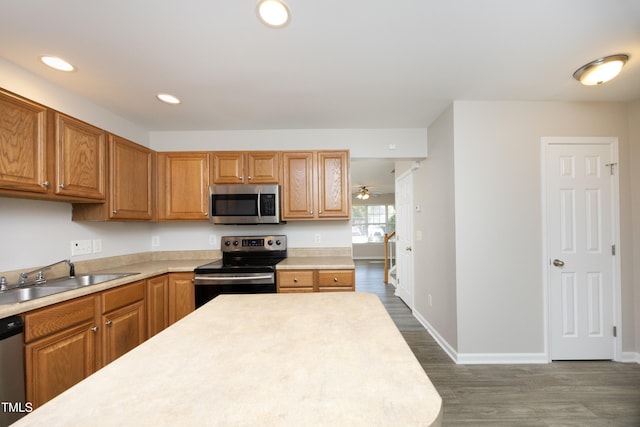 kitchen with dark wood-type flooring, ceiling fan, appliances with stainless steel finishes, and sink