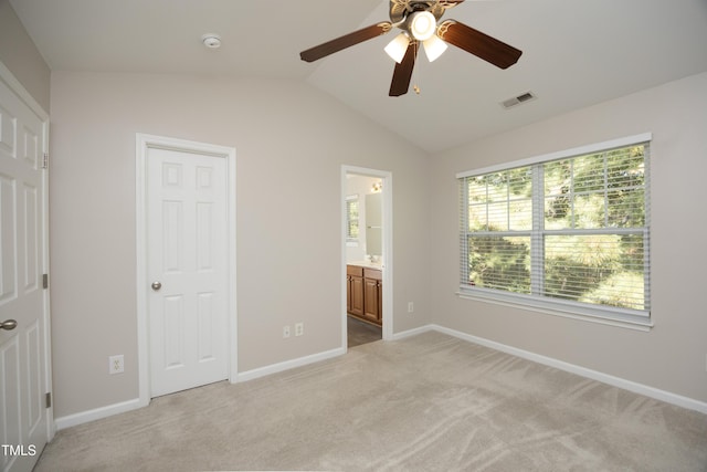 unfurnished bedroom featuring ceiling fan, ensuite bathroom, vaulted ceiling, and light carpet