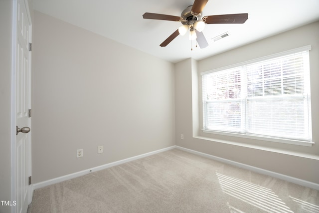 spare room featuring light carpet, a wealth of natural light, and ceiling fan