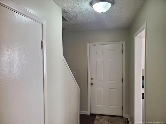 doorway to outside featuring a textured ceiling