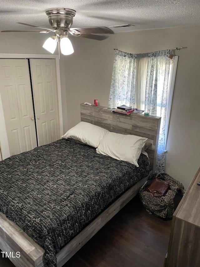 bedroom featuring a closet, dark hardwood / wood-style floors, a textured ceiling, and ceiling fan