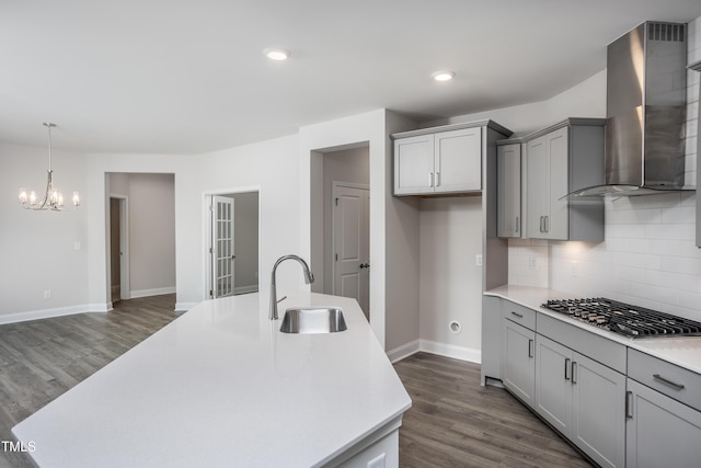 kitchen featuring wall chimney exhaust hood, stainless steel gas cooktop, sink, a center island with sink, and dark hardwood / wood-style floors