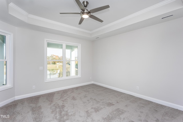 carpeted spare room featuring a tray ceiling, ceiling fan, and ornamental molding