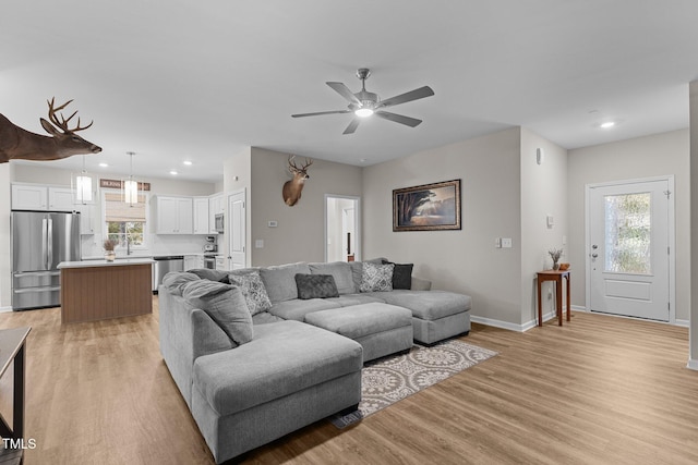 living room with light hardwood / wood-style floors, ceiling fan, and plenty of natural light