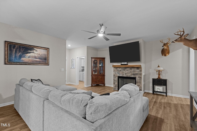 living room featuring hardwood / wood-style floors, ceiling fan, and a fireplace