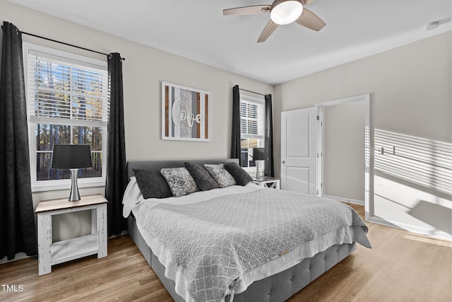 bedroom with multiple windows, hardwood / wood-style floors, and ceiling fan