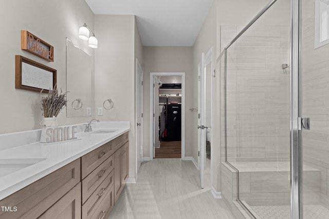 bathroom featuring a shower with door and vanity