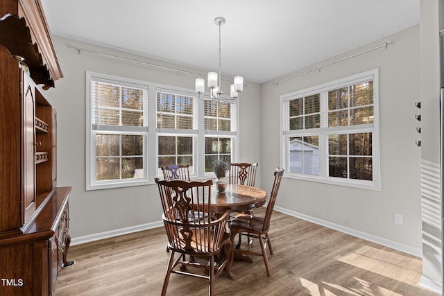 dining area with light hardwood / wood-style flooring and an inviting chandelier