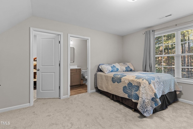 carpeted bedroom featuring ensuite bathroom and vaulted ceiling