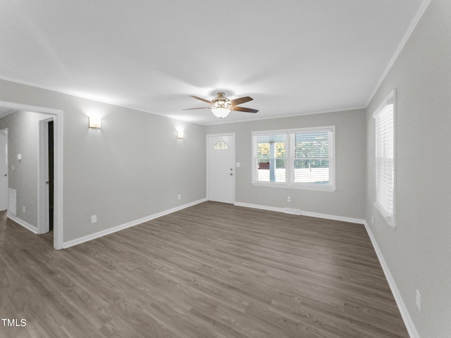 empty room with ornamental molding, dark wood-type flooring, and ceiling fan