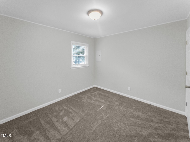 spare room featuring ornamental molding and dark colored carpet