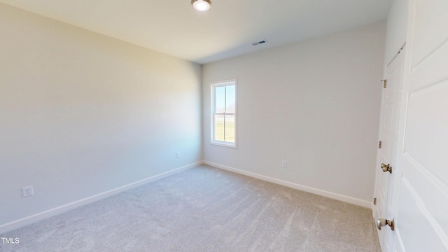 spare room with baseboards, visible vents, and light carpet