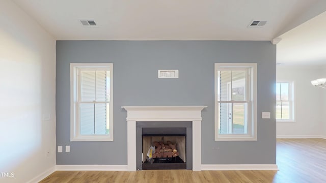 unfurnished living room featuring visible vents, baseboards, wood finished floors, and a fireplace