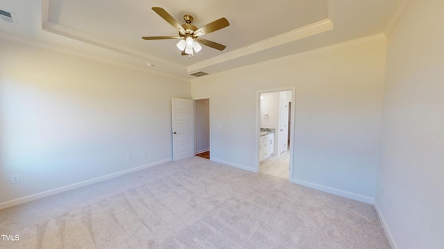 empty room with a raised ceiling, ceiling fan, baseboards, ornamental molding, and light carpet