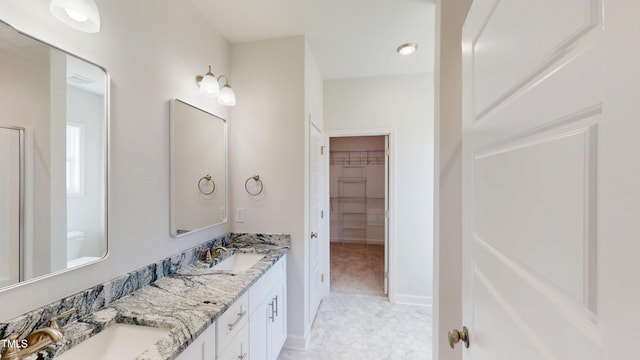 bathroom featuring double vanity, a spacious closet, and a sink