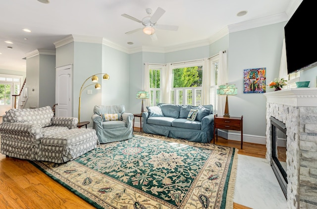 living room with ceiling fan, ornamental molding, light hardwood / wood-style flooring, and a fireplace