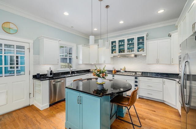 kitchen with white cabinetry, decorative light fixtures, stainless steel appliances, and a kitchen island