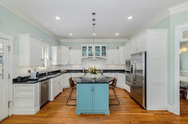 kitchen with light hardwood / wood-style floors, appliances with stainless steel finishes, a center island, and a kitchen breakfast bar