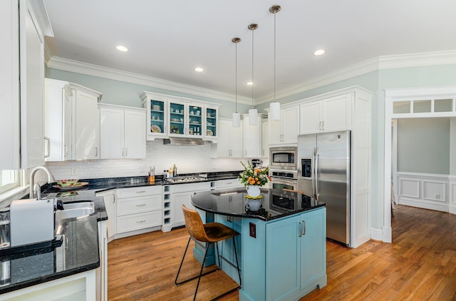 kitchen featuring a kitchen island, hardwood / wood-style flooring, hanging light fixtures, white cabinets, and appliances with stainless steel finishes