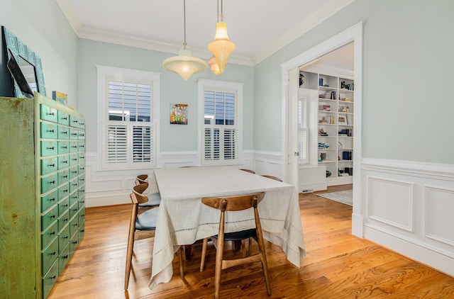 dining room featuring ornamental molding, light wood-type flooring, and built in shelves