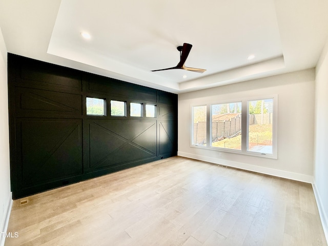 unfurnished room featuring light hardwood / wood-style flooring, a raised ceiling, and ceiling fan