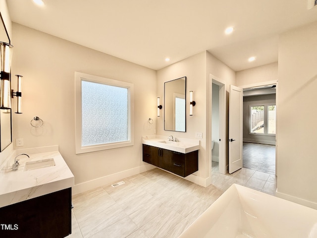 bathroom featuring vanity, a washtub, and toilet