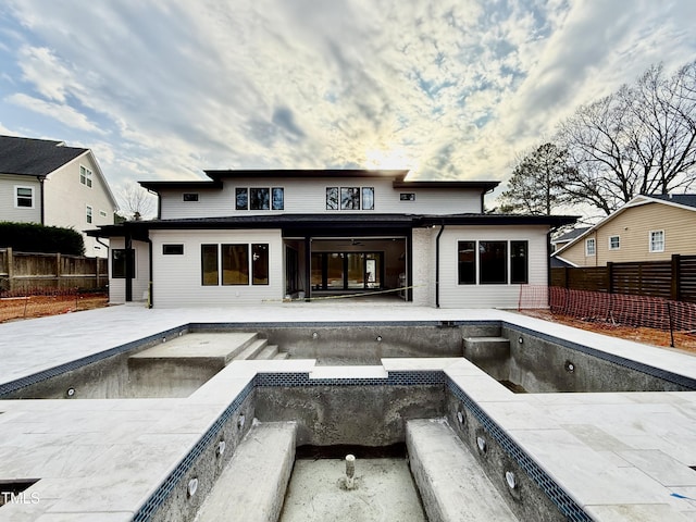 rear view of property featuring a pool with connected hot tub and a fenced backyard