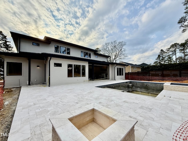 rear view of house with a patio, an empty pool, and a fire pit