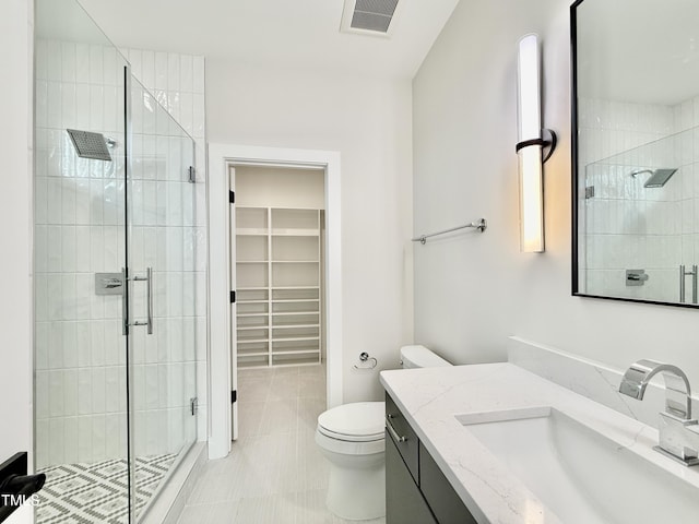 bathroom featuring tile patterned floors, vanity, toilet, and a shower with shower door