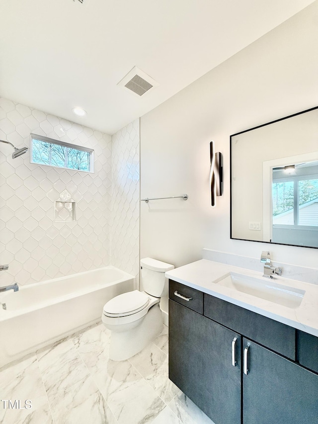 full bathroom featuring tiled shower / bath, vanity, toilet, and a wealth of natural light