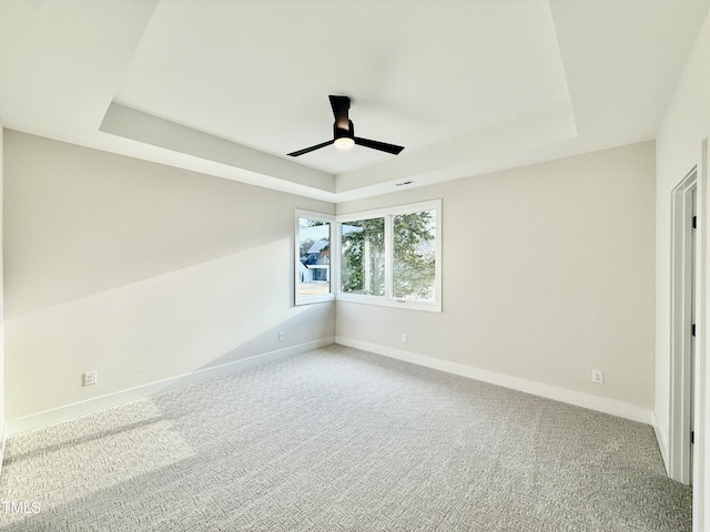 carpeted empty room featuring a raised ceiling and ceiling fan