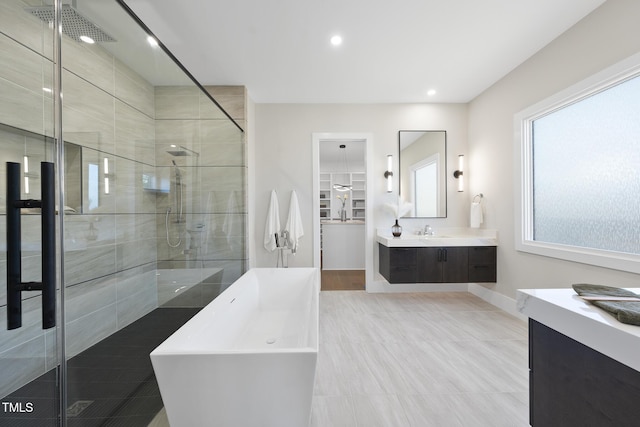 full bathroom with recessed lighting, vanity, baseboards, a soaking tub, and a shower stall