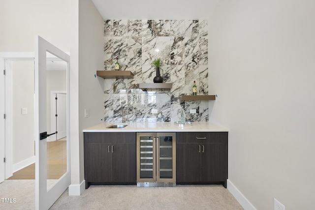 bar with beverage cooler, wet bar, baseboards, and a sink