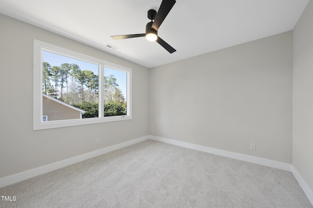 carpeted spare room featuring baseboards, visible vents, and a ceiling fan