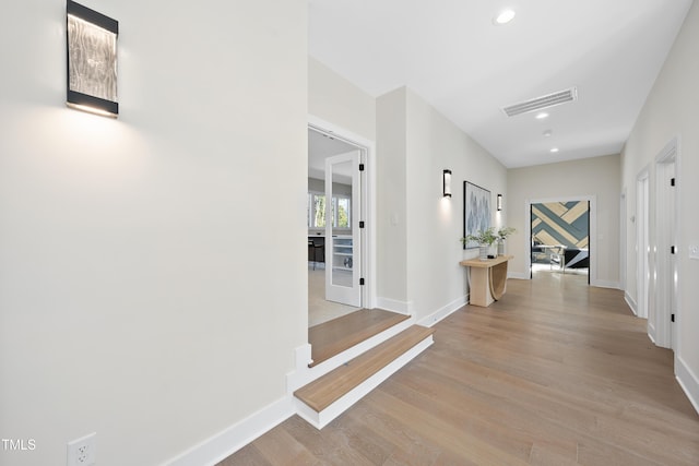 hall with light wood-style floors, recessed lighting, visible vents, and baseboards