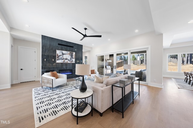 living area with light wood-style floors, recessed lighting, baseboards, and a tiled fireplace