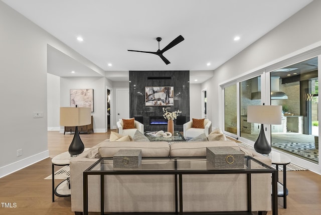 662 Manchester Dr, Raleigh, NC 27609 - living room with ceiling fan, a tiled fireplace, wood finished floors, recessed lighting, and baseboards