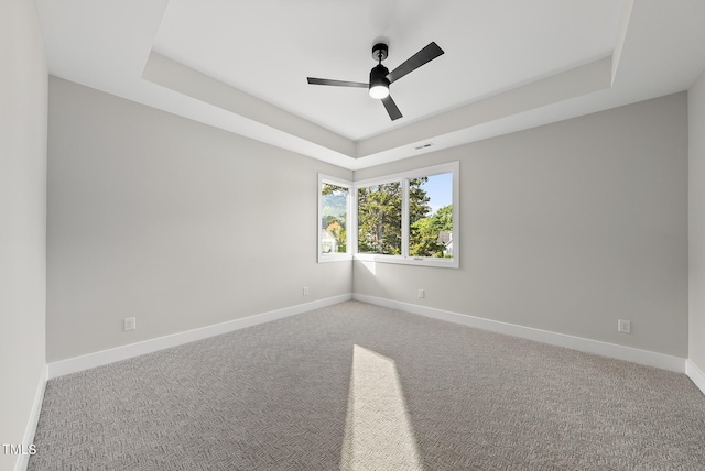 662 Manchester Dr, Raleigh, NC 27609 - unfurnished room with a tray ceiling, baseboards, a ceiling fan, and carpet flooring