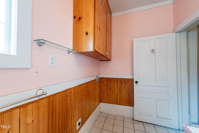 laundry room with light tile patterned floors, cabinets, and wood walls