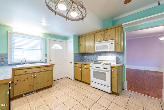 kitchen featuring backsplash, light wood-type flooring, sink, decorative light fixtures, and white appliances