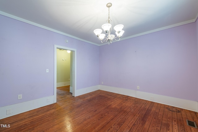 spare room with hardwood / wood-style floors, crown molding, and an inviting chandelier