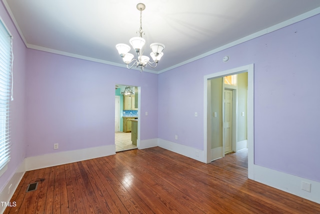 unfurnished room with ornamental molding, hardwood / wood-style floors, and an inviting chandelier