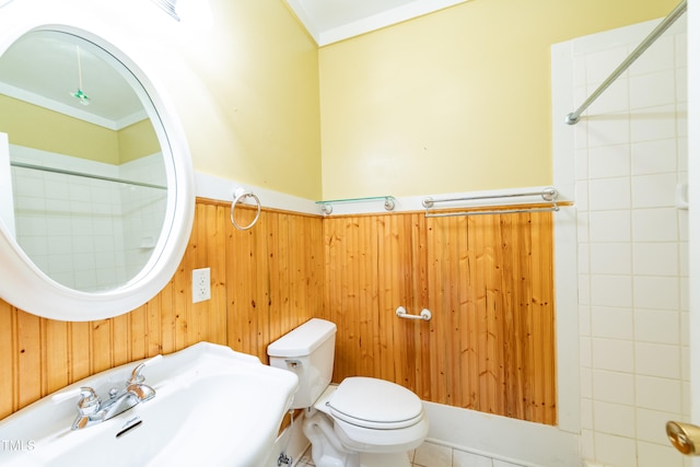 bathroom with toilet, wooden walls, sink, and tiled shower